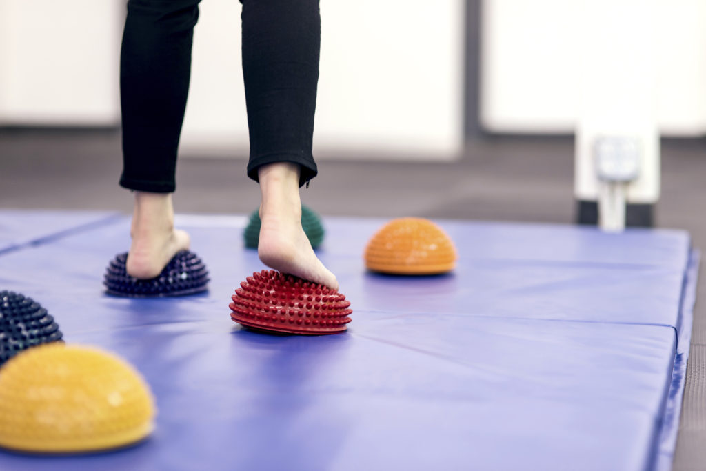 Feet stepping on therapy balls to practice balance at a PT clinic